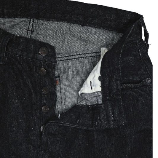 Close-up of a black denim jacket with a button detail on a white background