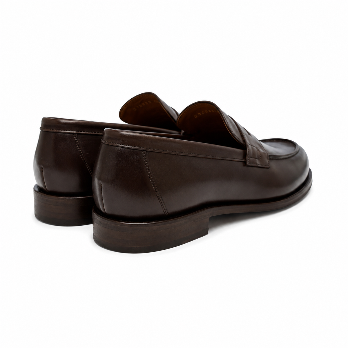 A pair of dark brown leather penny loafers shown from a three-quarters rear angle on a clean white background.