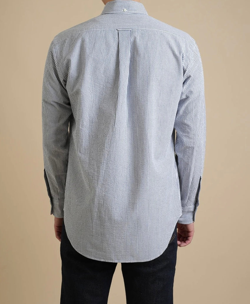 Back view of a person wearing a gray and white striped shirt on a beige background