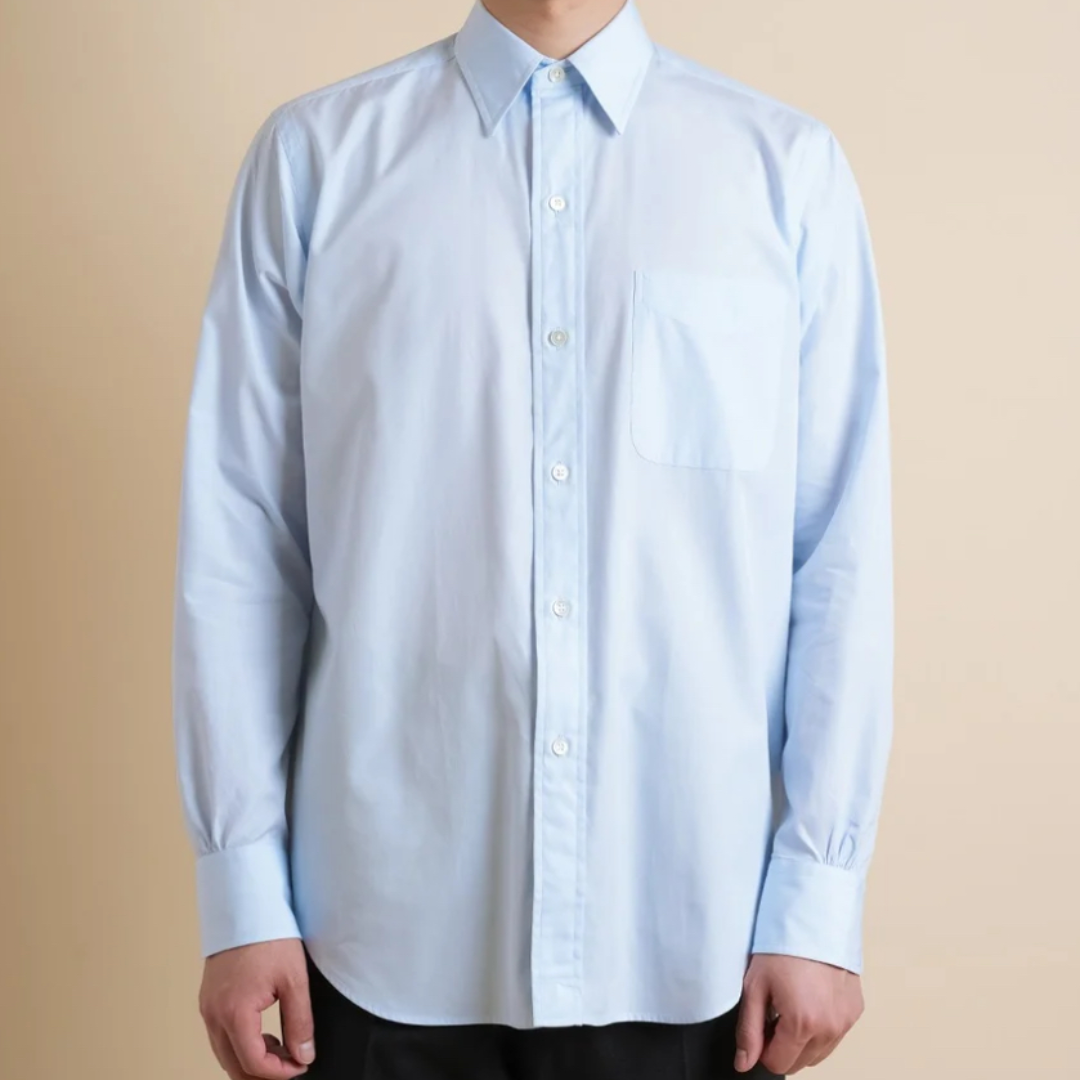 Light blue button-up shirt worn by a person on a beige background