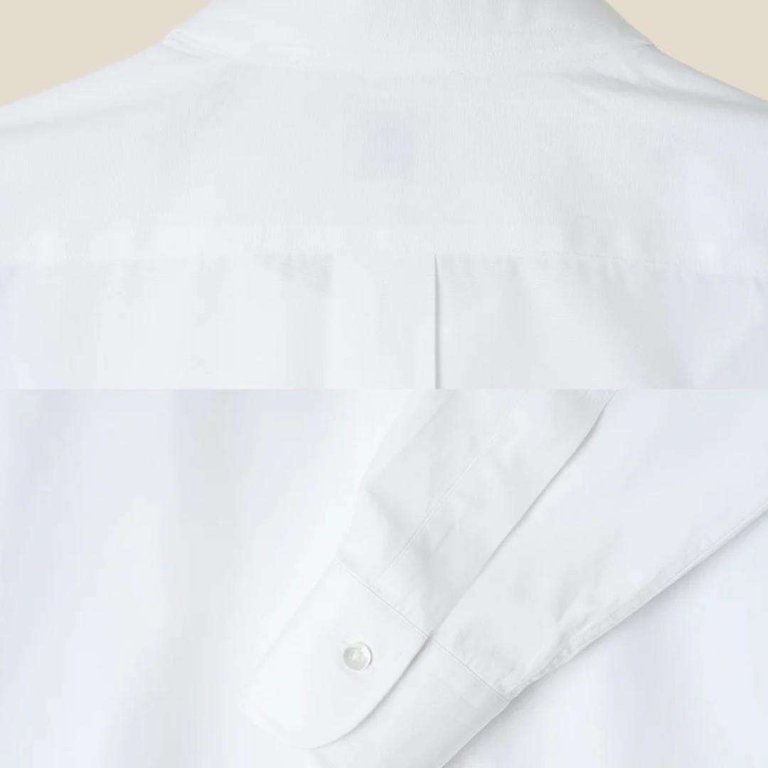 Close-up of a white shirt with a collar and button detail on a light background
