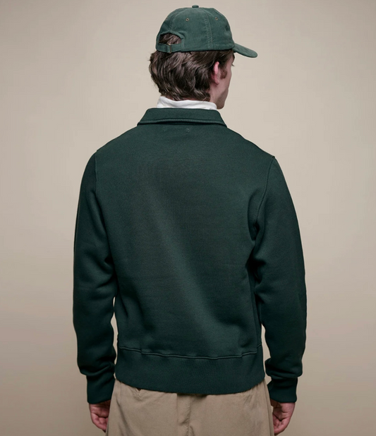 Person wearing a green jacket and cap on a beige background