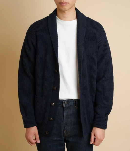Person wearing a dark blue cardigan over a white shirt with a beige background