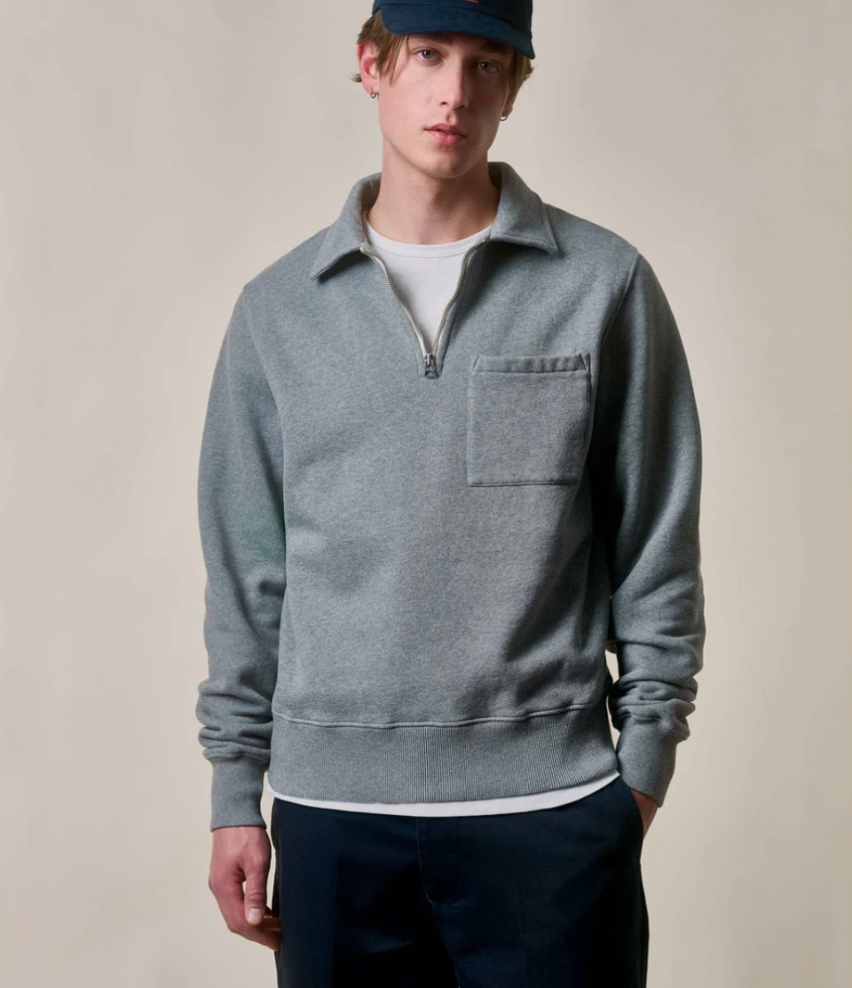 Man wearing a gray pullover with a zipper on a beige background
