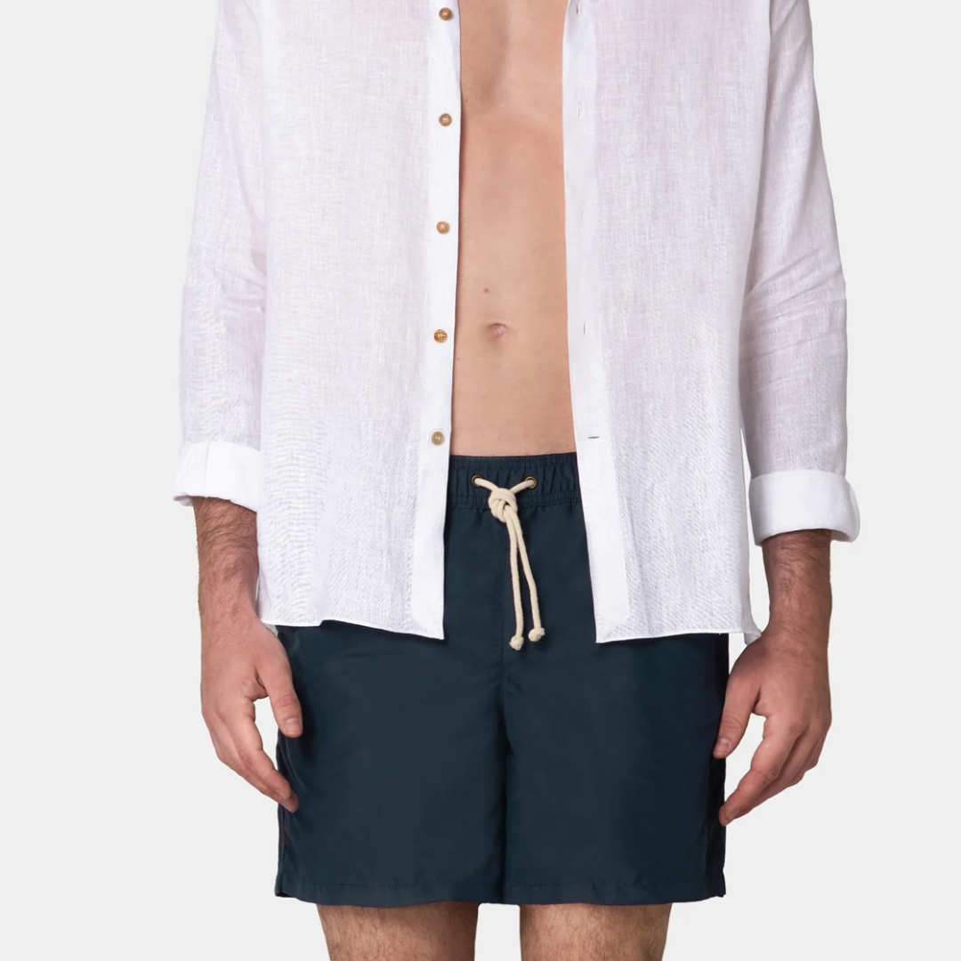 Person wearing navy shorts with a white shirt on a white background