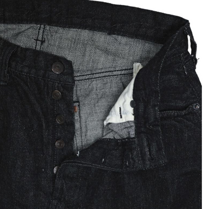 Close-up of a black denim jacket with a button detail on a white background