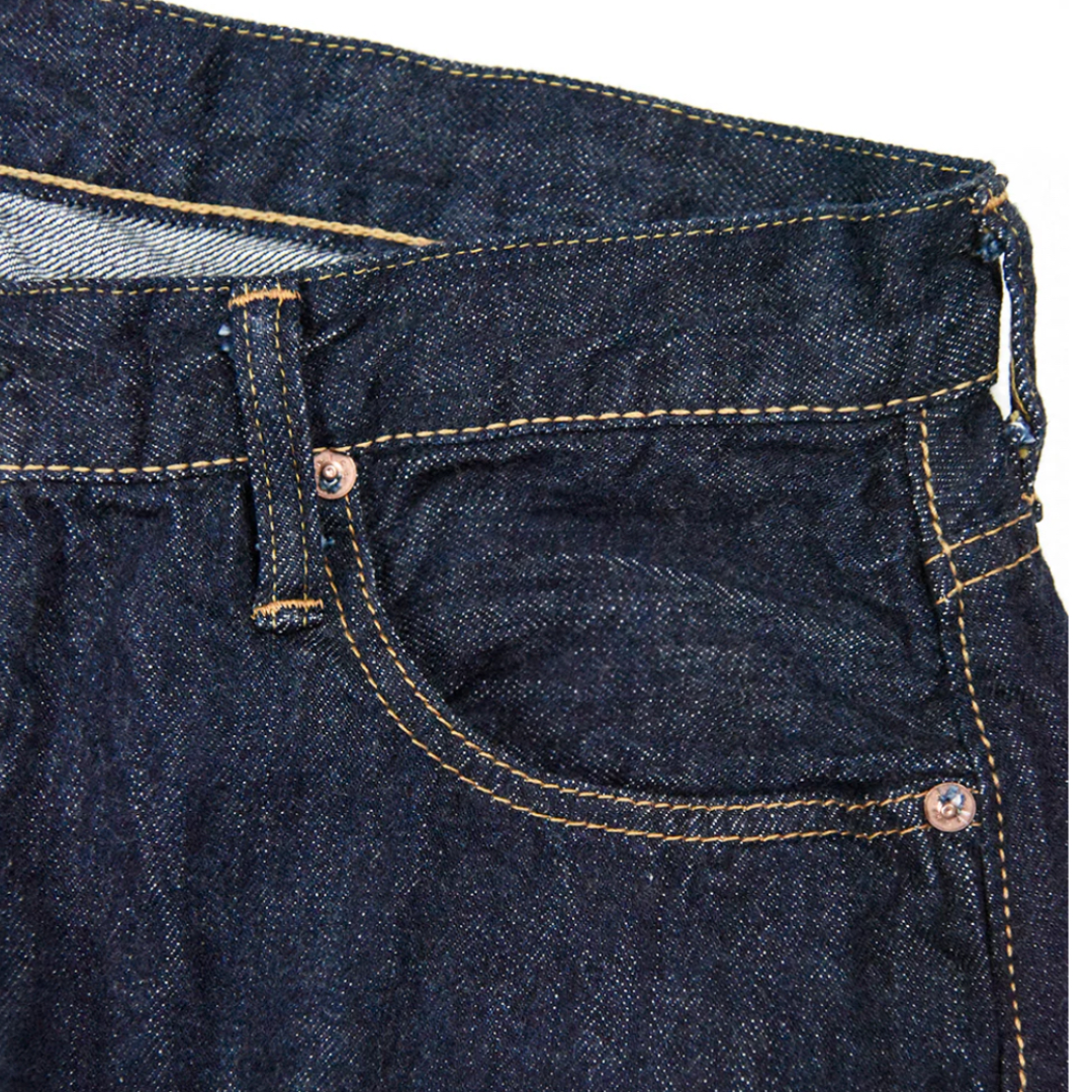 Close-up of dark blue denim jeans with stitching details on a white background