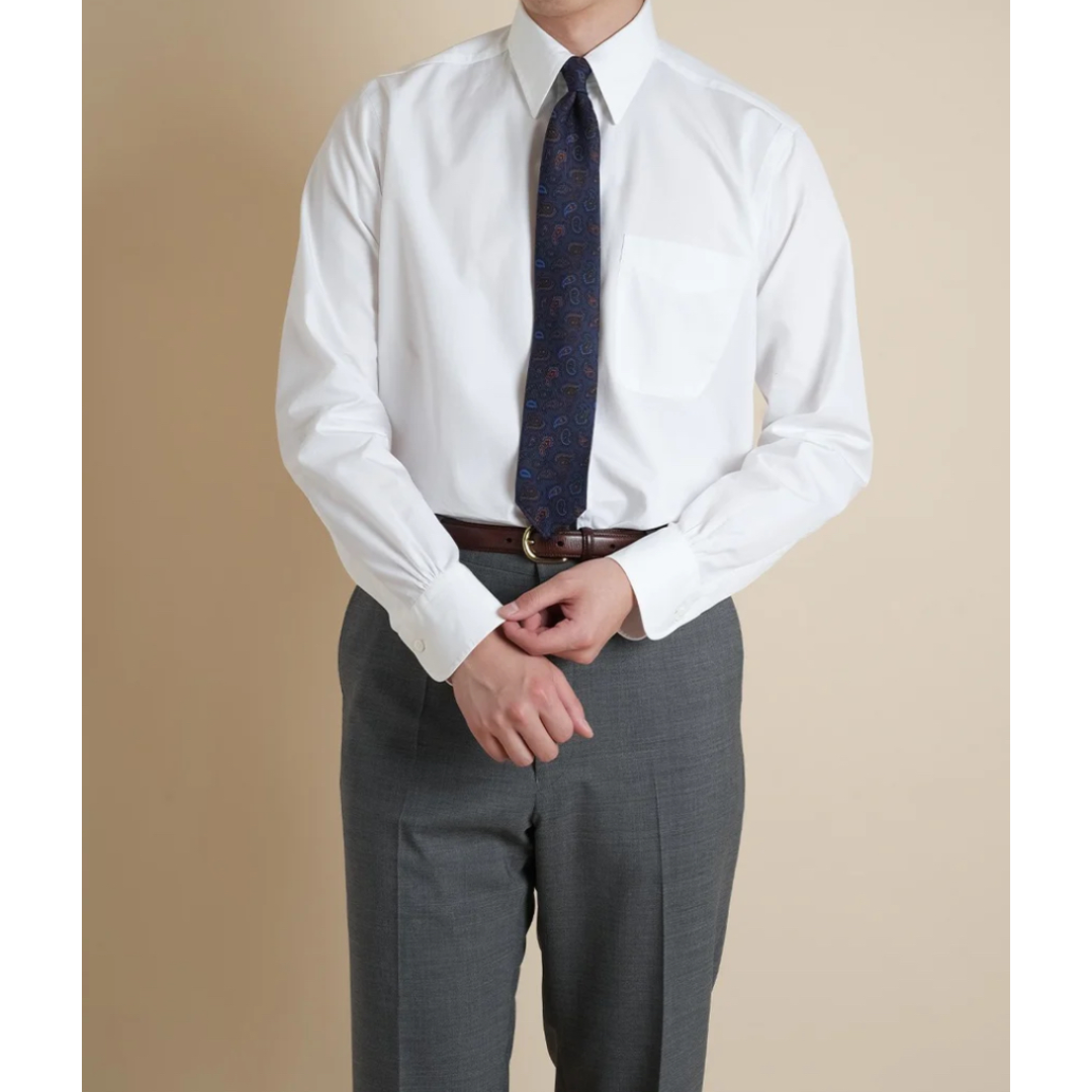 Person wearing a white dress shirt, gray pants, and a patterned tie against a beige background