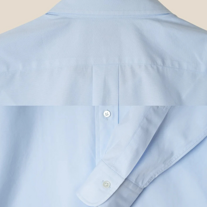 Light blue shirt with a button detail on a beige background