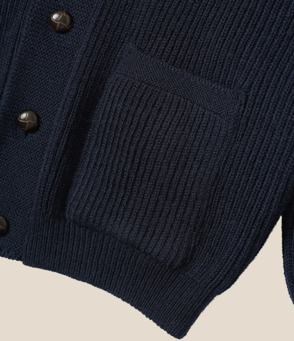 Navy blue cardigan with button details on a beige background