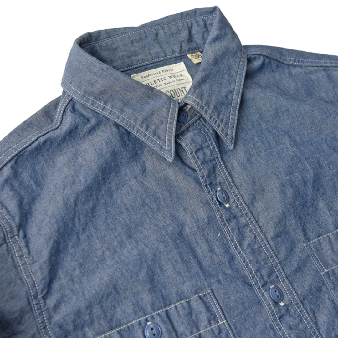 Close-up of a blue denim shirt with collar and brand label.