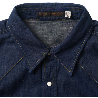 Close-up of a blue denim shirt collar with a brand label on a white background
