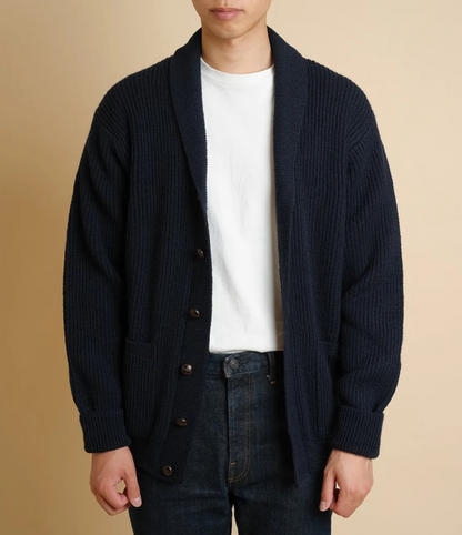 Person wearing a dark blue cardigan over a white shirt with a beige background