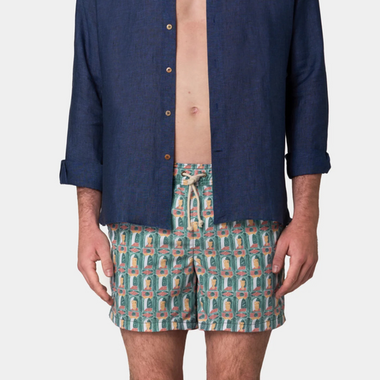 Person wearing a navy shirt and patterned shorts on a white background