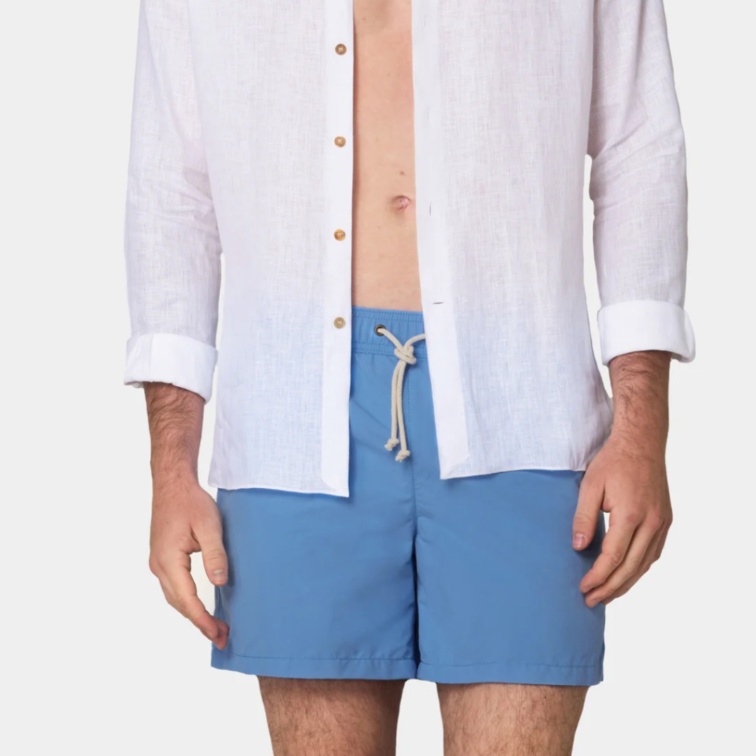 Person wearing a white shirt and blue shorts on a plain background