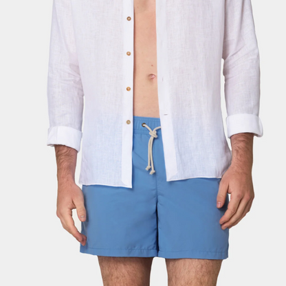 Person wearing a white shirt and blue shorts on a plain background