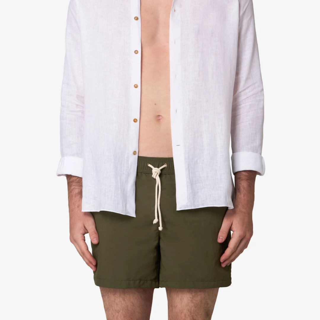Person wearing a white shirt and green shorts on a white background