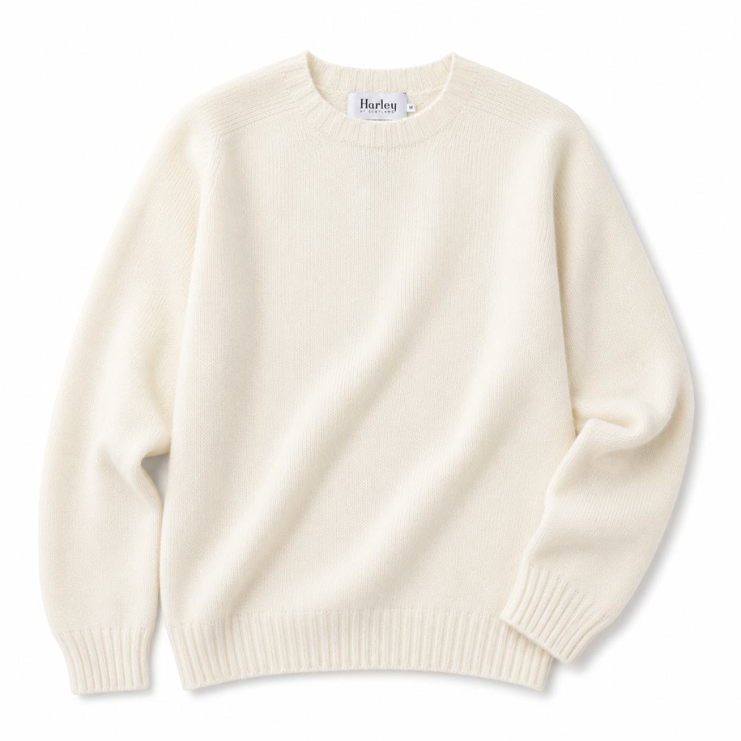An off-white cream knit crewneck sweater with long sleeves and ribbed cuffs and hem, shown flat on a white background. The brand label inside the collar reads 'Harley'.