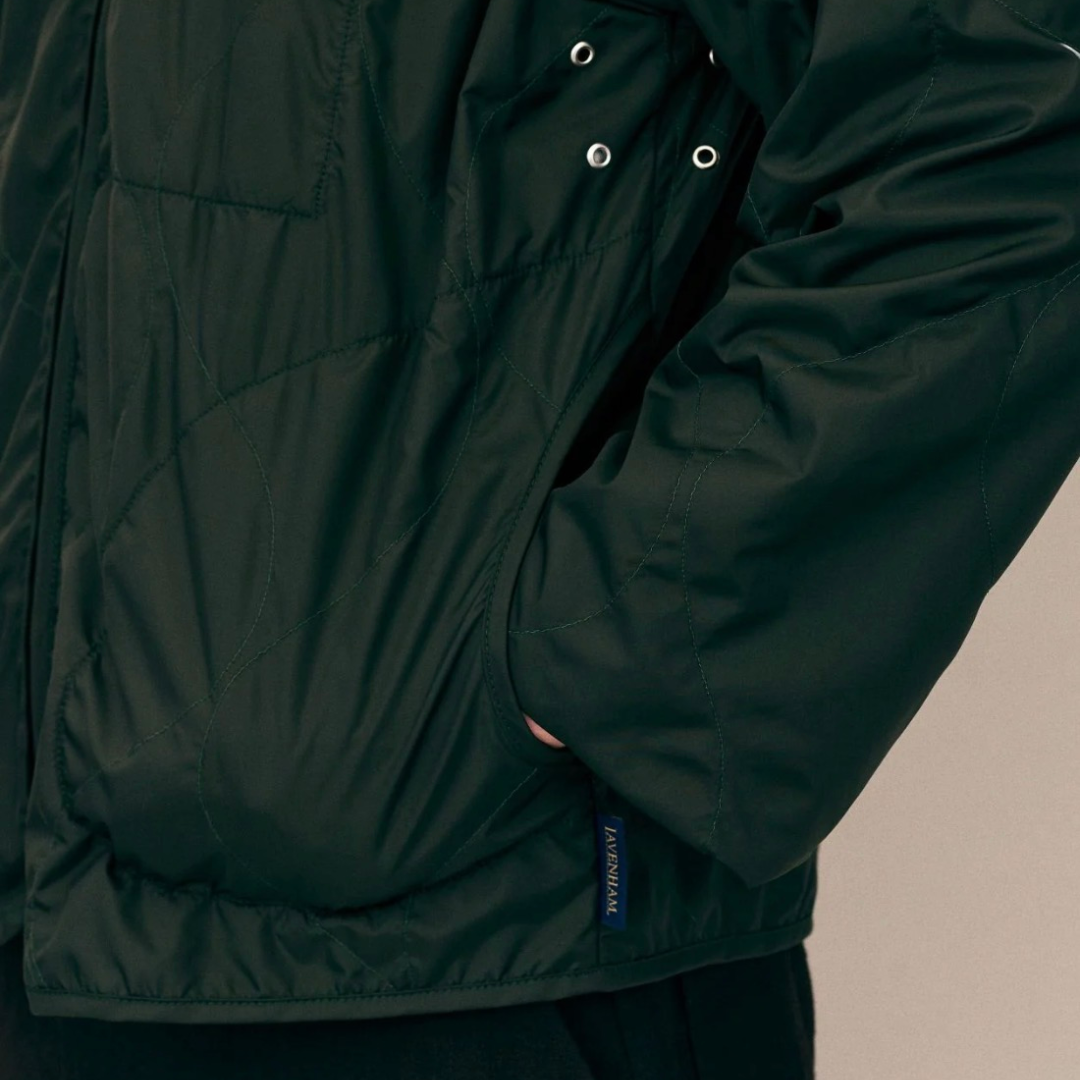 Lavenham olive windbreaker jacket, lightweight outerwear with hood and front pockets, displayed on a hanger.