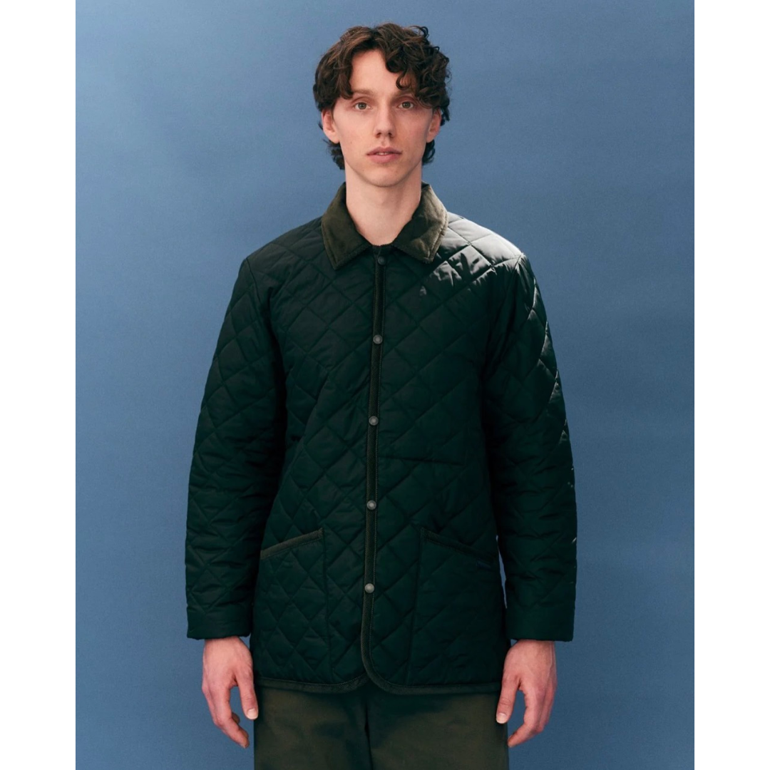 Man wearing a dark green quilted jacket against a blue background