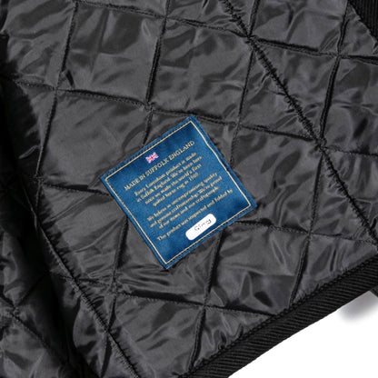 Black quilted jacket with a blue label on a white background