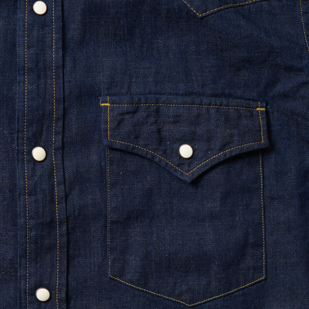 Close-up of a dark blue denim shirt with a pocket and buttons.